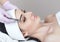 There is a woman, who is making the procedure Microdermabrasion of the facial skin in a beauty salon