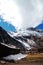 There is a wooden house at the foot of the huge glacier