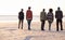 Theres place for one more explorer. a group of friends walking along a beach at sunset.