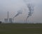 thermal power station with smoking chimney in winter evening green grass foreground