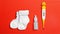 Thermometer, baby socks and nasal drops for illness on orange background. Baby care