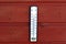 Thermometer displaying high temperatures hanging on a reddish wooden wall