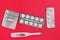 Thermometer and silver blisters with pills on a red background. Pharmacy and medical concept. Flat lay