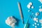 Thermometer, syringe, ampoules, pills and crumpled paper napkin on blue paper background. Concept of common cold, covid