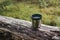 Thermos green plastic stainless steel mug on a log