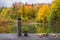 Thermos on a wooden table near the lake in the autumn forest. Beautiful autumn landscape