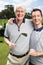 Theyre big golfing fans. Father and son golfing team on the green with their golf cart in the background.