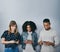 Theyre connected to the same wireless network. Studio shot of three young people using their cellphones against a grey