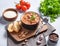 Thick beef or lamb kharcho soup with rice, tomato, walnuts and spices in a bowl on a light background with fresh tomatoes, herbs