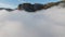 Thick clouds near high mountains. Shot. Beautiful clearing of clouds on background of mountain peaks and blue sky. Sunny