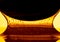 Thick drops of honey flowing down from a dark black spoon on yellow background. Golden streams of honey molasses or