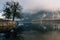 Thick, eerie fog creeping over the water of Lake Halschat in Austria