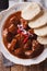 Thick goulash with dumplings on a plate close-up. vertical top v