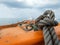 Thick grey rope tied to small orange boat