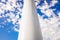 Thick metallic white pipe in vertical position as base of a tower, isolated on blue sky background