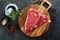 Thick Raw T-Bone Steak. Dry-aged Raw T-bone or porterhouse beef meat Steak on cutting boar with herbs and salt on dark