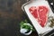Thick Raw T-Bone Steak. Dry-aged Raw T-bone or porterhouse beef meat Steak on parchment paperwith herbs and salt on dark