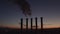 Thick smoke rises high. Environmental pollution through chimneys. Silhouette of five pipes. Beautiful sunset over a