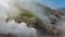 Thick steam from an erupting geyser swirls over the hillsides.