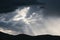 Thick stormy clouds over the mountains with intense sun rays peaking through and contrasty light