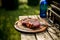 A thick strip steak being grilled outdoors