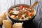 Thick tomato fish soup with eel and vegetables closeup in a bowl served with bread. horizontal