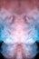 A thick vertical column of smoke dissipates dimly on a black background painted in pink and blue, evaporates like a cloud from a