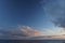 Thick white clouds over the horizon as the sun sets on the North Pacific Ocean