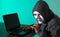 Thief hacker in mask stealing personal information from laptop