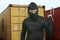 Thief at work - criminal man in black covered with balaclava mask holding unlocked padlock at shipping area break in storage