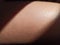 Thigh of a girl with a ray of sun. Closeup tanned skin in