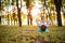 Thin brunette girl plays sports and performs yoga poses in autumn park on a sunset background. Woman doing exercises on the yoga