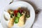 Thin crepes stuffed with spinach and mushrooms. With basil, arugula, violet flowers and sour cream. The dish is served on a table