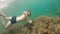 A thin man with a beard in a mask swims underwater, waving his arms. Close-up.