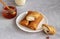 thin pancakes envelope filled with cottage cheese and raisins on a saucer with honey on a gray background