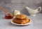 thin pancakes envelope filled with cottage cheese and raisins on a saucer with honey on a gray background