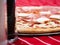 Thin pizza portion with high meat content and salt and pepper shaker. Uncooked product with cheese, salami, ham and tomato sous on