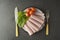 Thin slices of ham rolled on plate with fresh vegetables, dark background. Breakfast food, ingredient for sandwich. Flat lay food