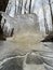 thin transparent ice on a puddle in the park on a winter day, foliage through the ice