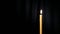 Thin wax candle burning on a black background with white beam