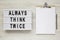 `Always think twice` words on a lightbox, clipboard with blank sheet of paper on a white wooden surface, top view. Overhead, fro