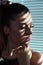 Thinking anxious woman with shadow on face of venetian blinds on window and hand on jaw