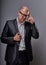 Thinking bald business man looking serious in eyeglasses having an idea and scratching the head in suit on grey background.