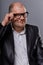 Thinking bald business man looking serious in eyeglasses in suit on grey background. Closeup