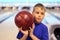 Thinking boy holds ball in bowling