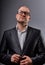 Thinking fun bald business man looking serious in eyeglasses in suit on grey background. Closeup