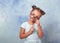 Thinking fun kid girl in glasses looking happy and holding eyeglasses and pen in the hands on blue background.