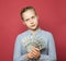 Thinking girl holding money us dollars on pink background. Teenager planning budget