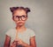 Thinking grimacing kid girl in glasses looking and holding pencil in hand on blue background with empty copy space. Toned vintage