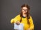 Thinking grimacing serious schoolgirl in eyeglasses holding excercise books on grey studio background. Back to school. The concept